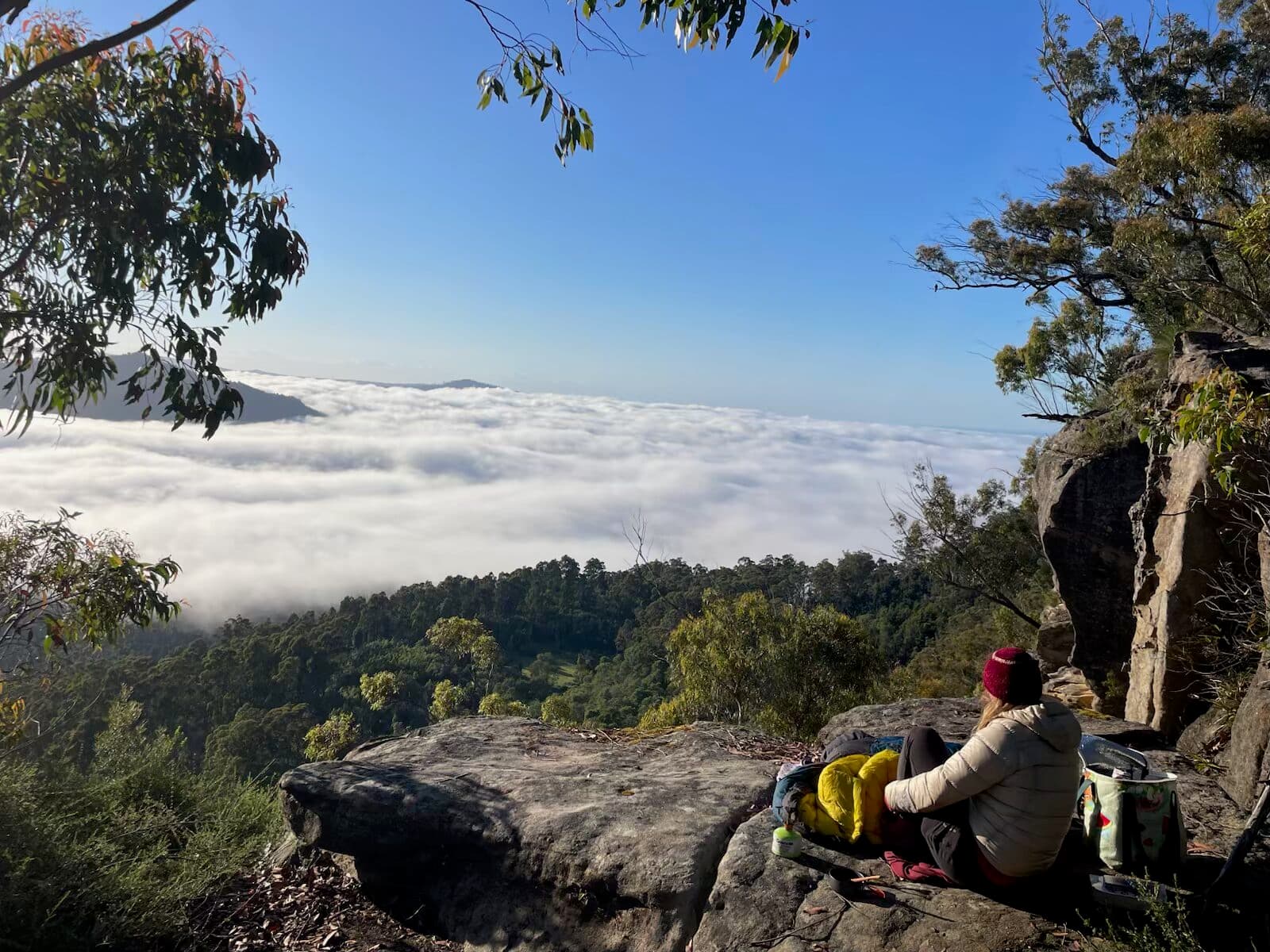 Participant resting at a cliff edge above the cloud-filled valley